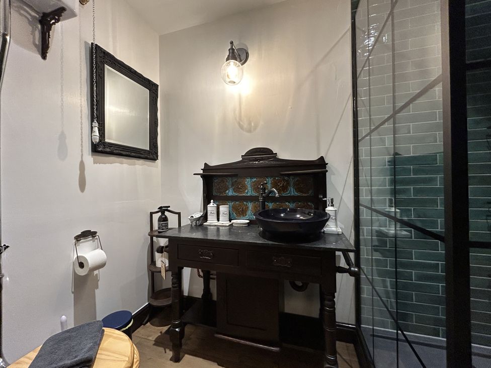 A bathroom with a black sink and mirror at The Salt Pot in Oakworth