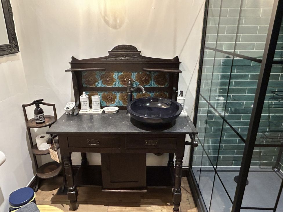 A bathroom with a sink and wooden cabinet at The Salt Pot in Oakworth