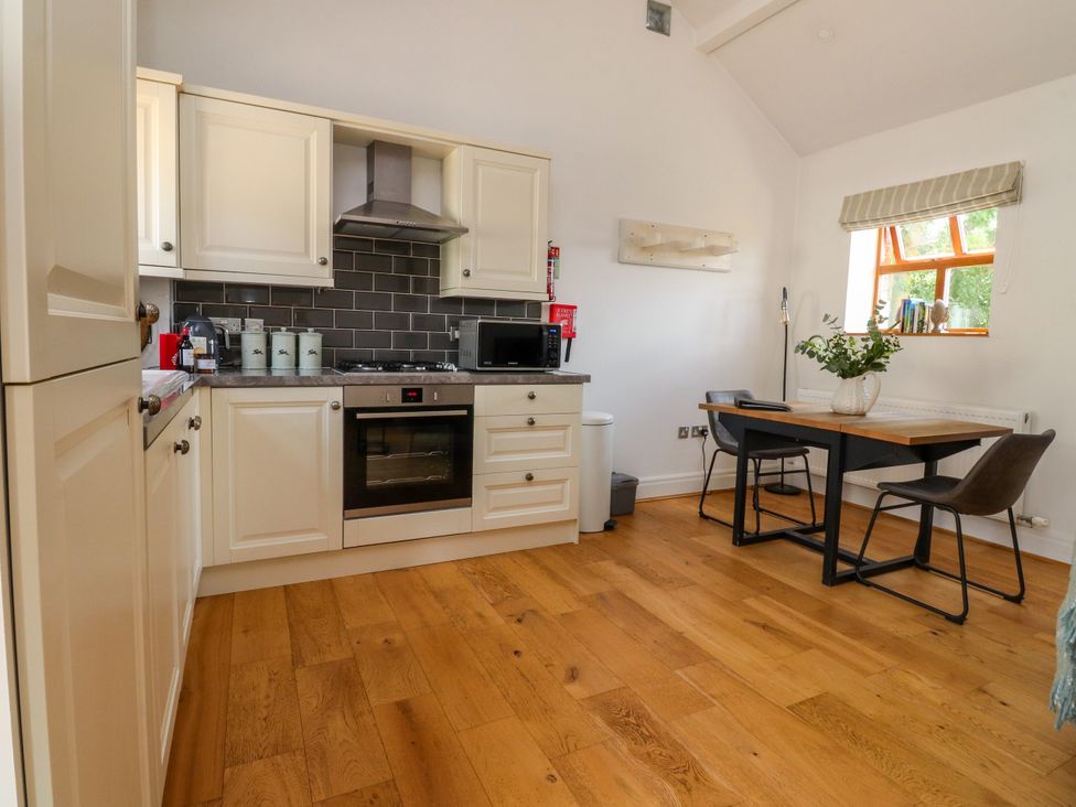 A kitchen with cabinets and a dining table at The Stables in Hall Green near Walmer Bridge