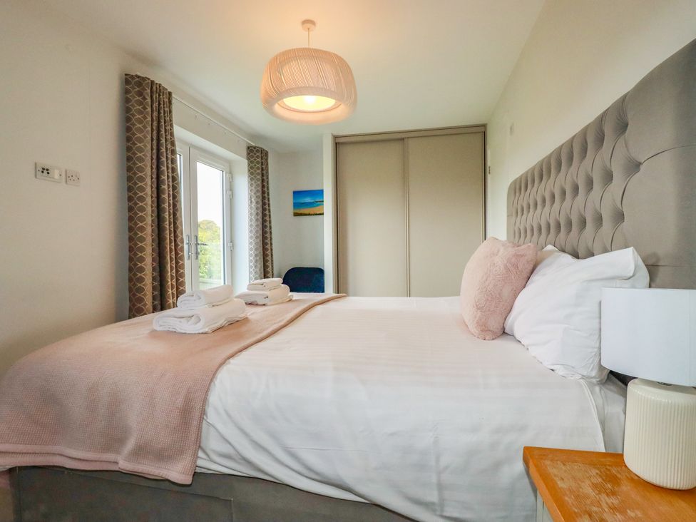 A bedroom with a bed and curtains at Chi Gwynn in Crantock
