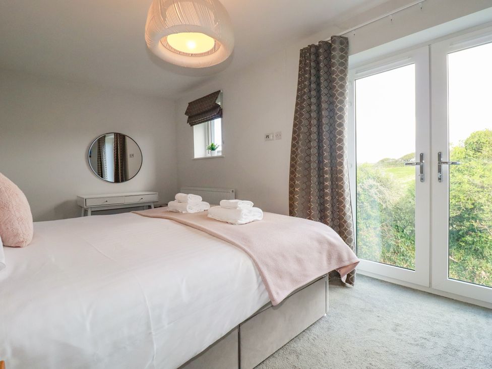 A bedroom with a bed and mirror at Chi Gwynn in Crantock