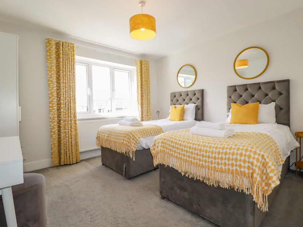 A bedroom with twin beds and a desk at Chi Gwynn in Crantock