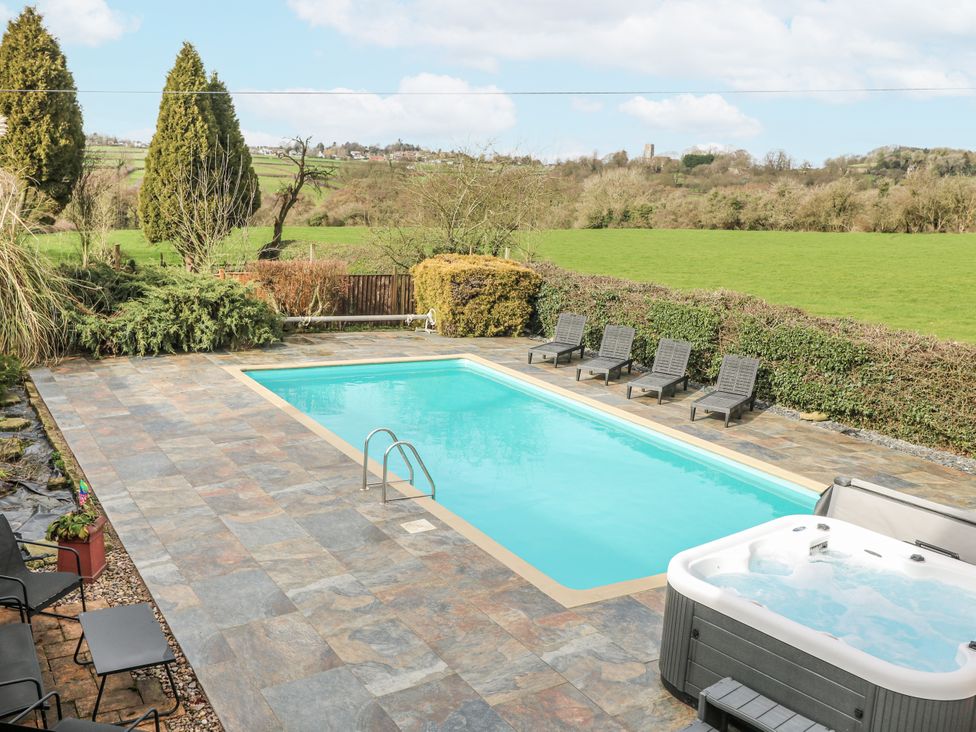 An outdoor area with a swimming pool and hot tub at Woodpit Cottage Watnall