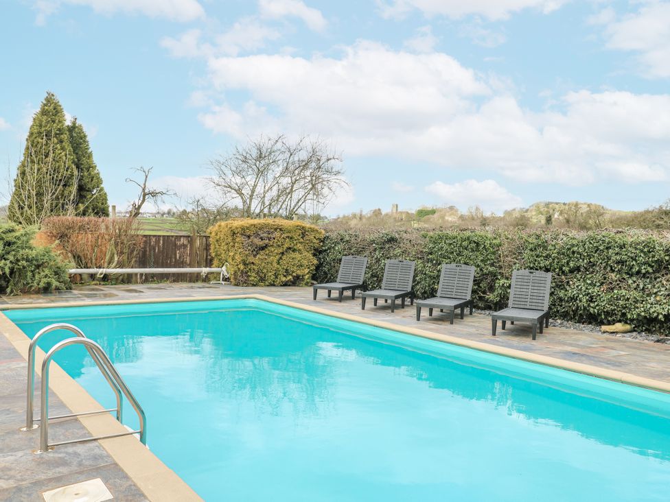 A swimming pool with sun loungers at Woodpit Cottage Watnall