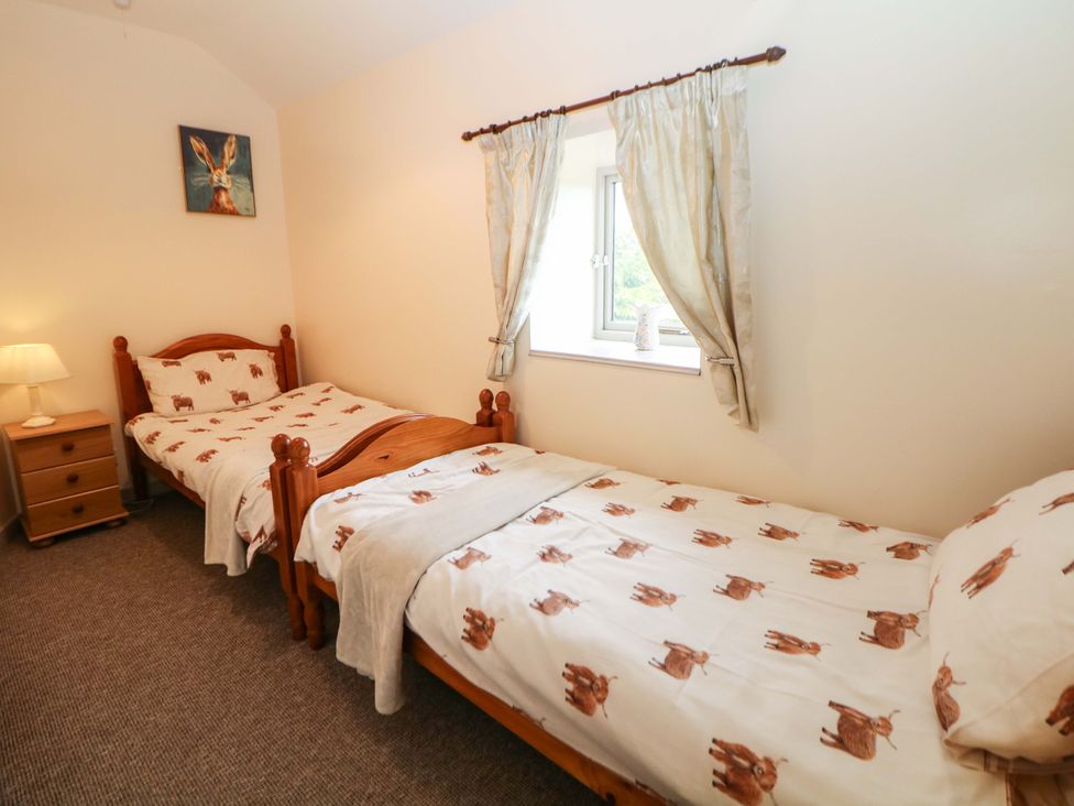 A bedroom with two single beds and a lamp at Ford Coach House Cottage in Ford near Leek