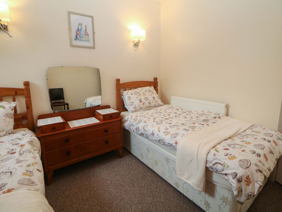 A bedroom with two beds and a mirror at Ford Coach House Cottage in Ford near Leek