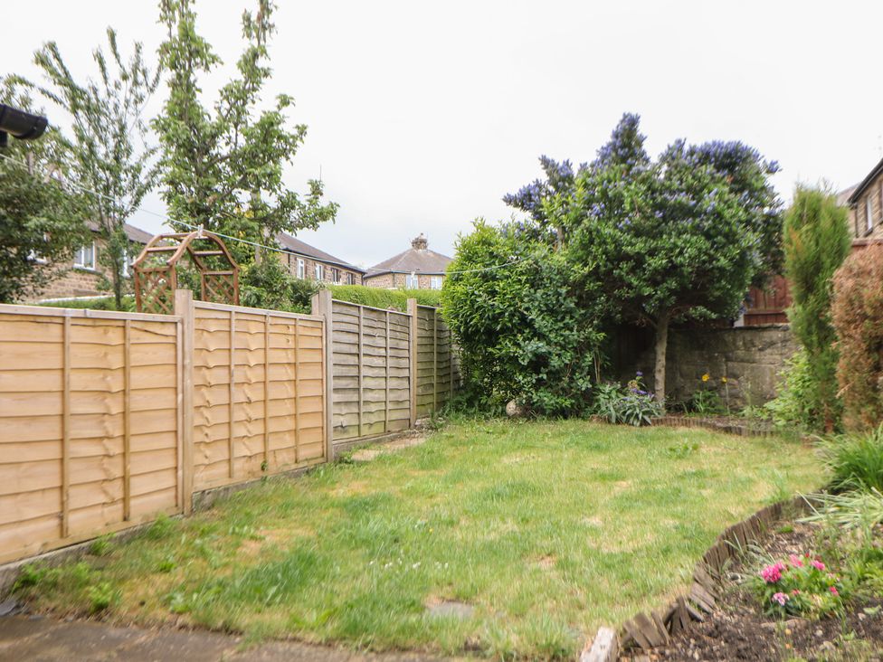 A garden with grass and trees at 15 Calton View in Bakewell
