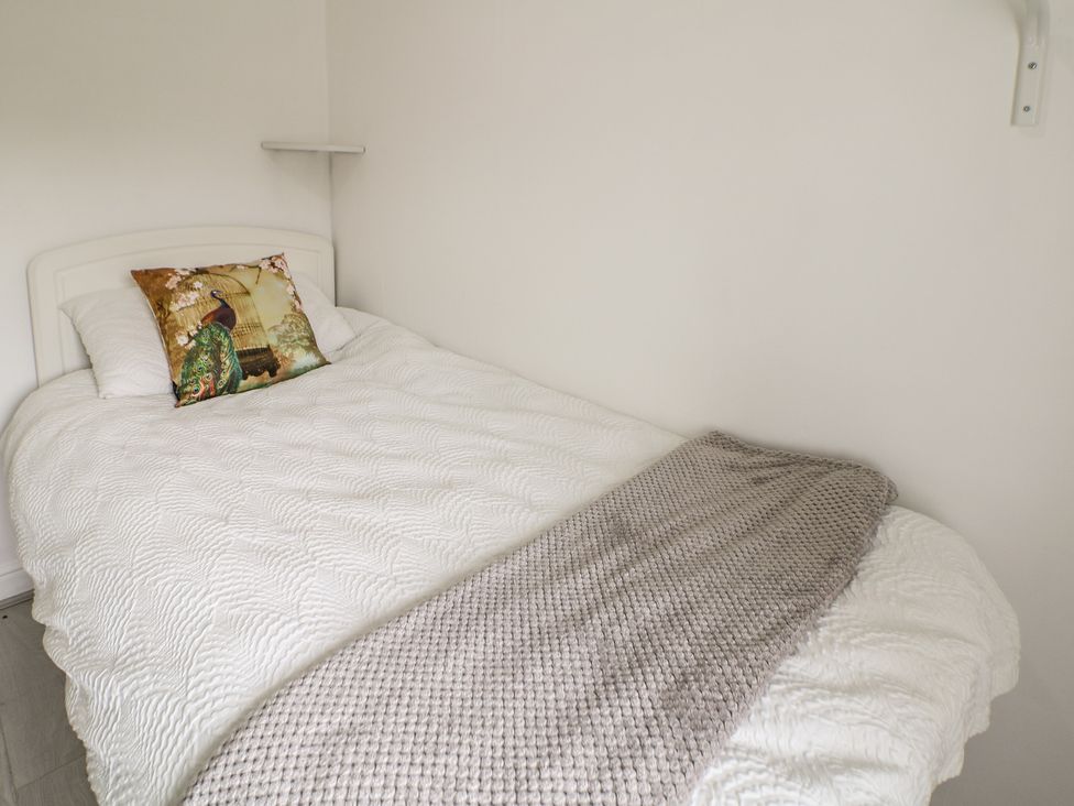 A bed with a cushion and blanket at Cherry Tree Cottage in Bakewell