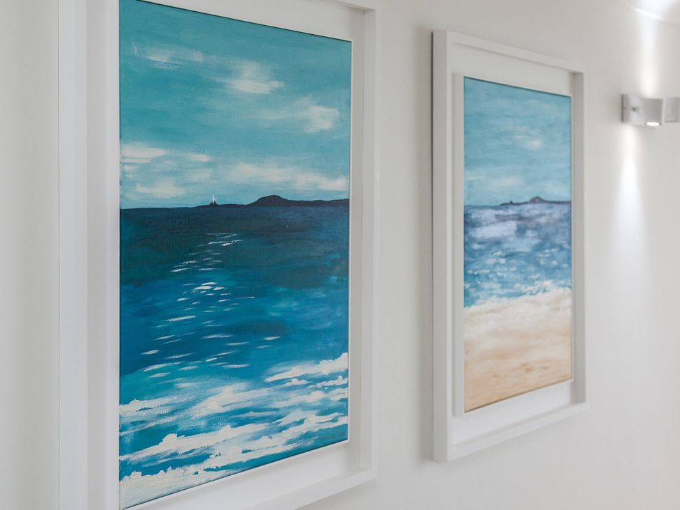Two ocean-themed paintings in white frames in a hallway at Ultramarine in Carbis Bay