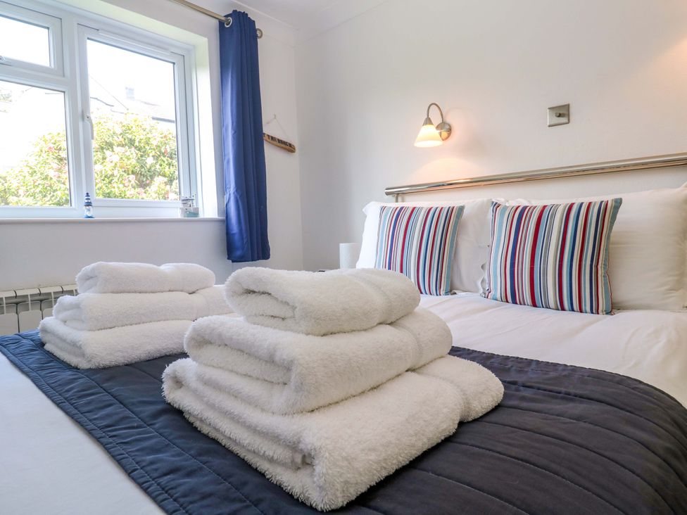 A bedroom with a bed and towels arranged at Atlantic Waves in Carbis Bay