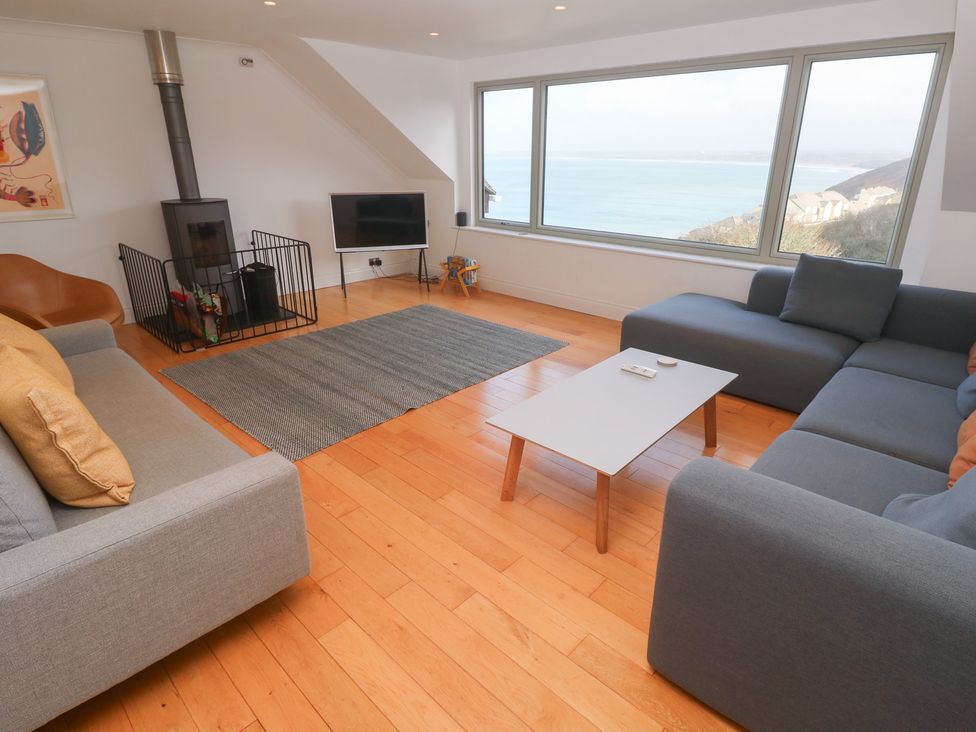 A living room with a sofa, fireplace, and television at Bayside in Carbis Bay