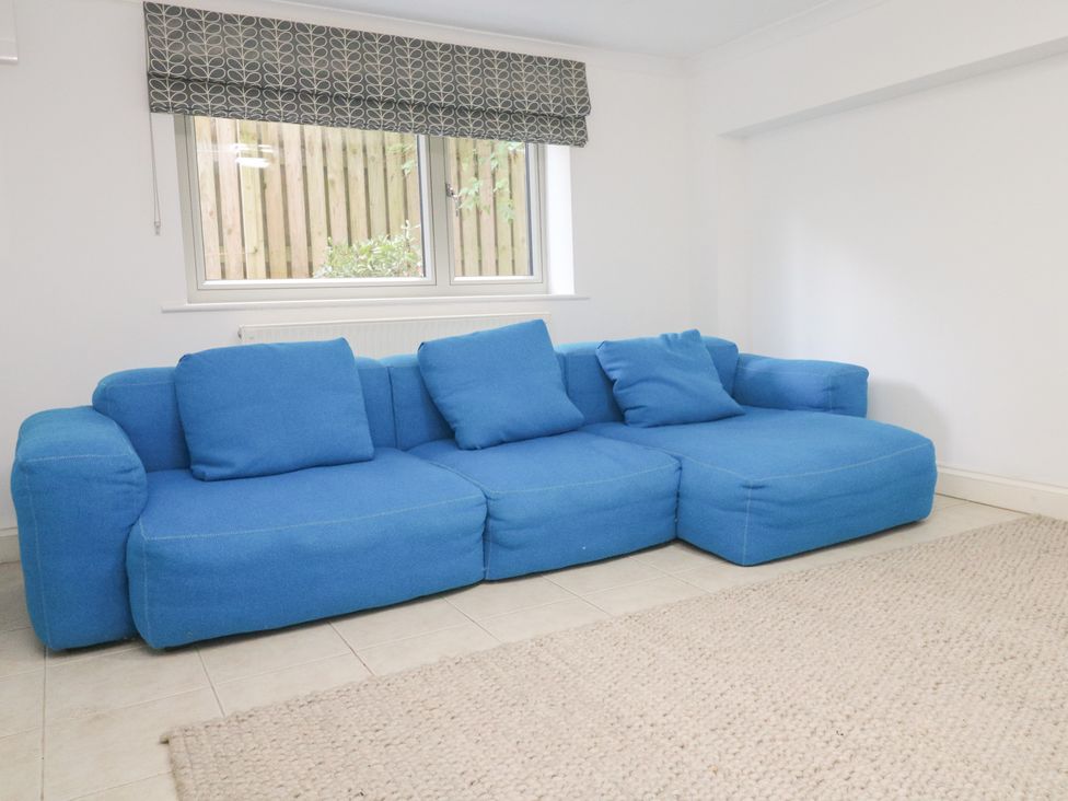 A living room with a blue couch and a window at Bayside in Carbis Bay