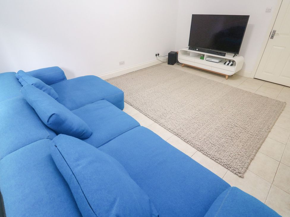 A living room with a blue couch and TV at Bayside Carbis Bay
