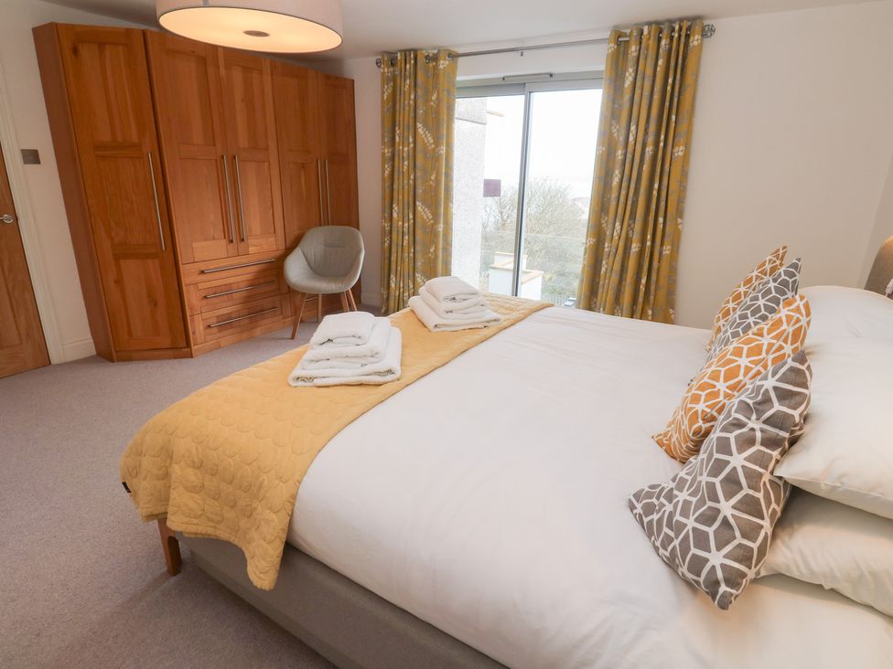 A bedroom with a bed and wooden wardrobe at Bayside in Carbis Bay