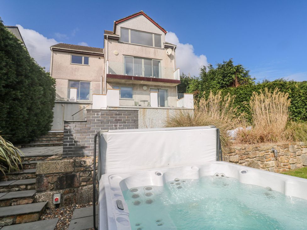 A hot tub in a garden with a house in the background at Bayside in Carbis Bay