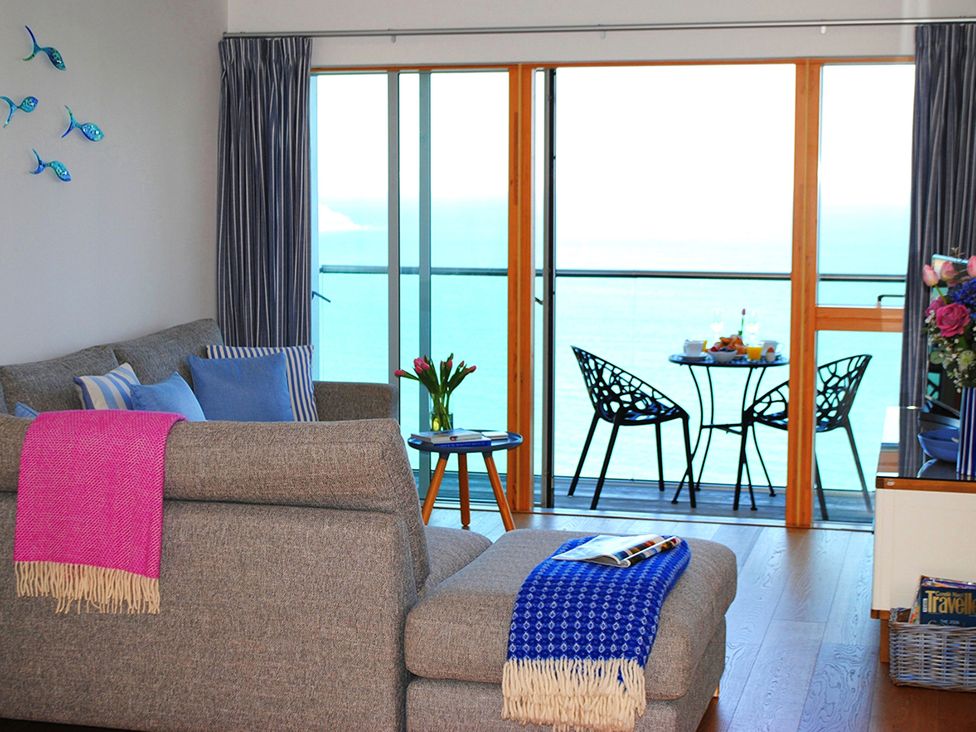 A living room with a sofa and balcony view at Sea Mist in Carbis Bay