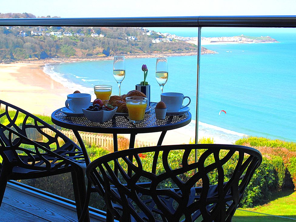 A balcony with table and chairs overlooking the beach at Sea Mist in Carbis Bay