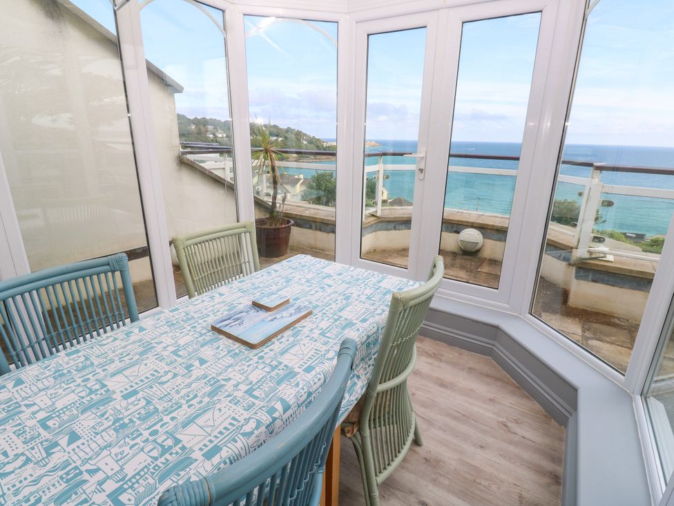 A conservatory with a table and chairs overlooking the sea at Ocean Gem in Carbis Bay