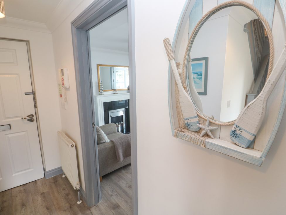 A hallway with a mirror and a view into a living room at Ocean Gem in Carbis Bay