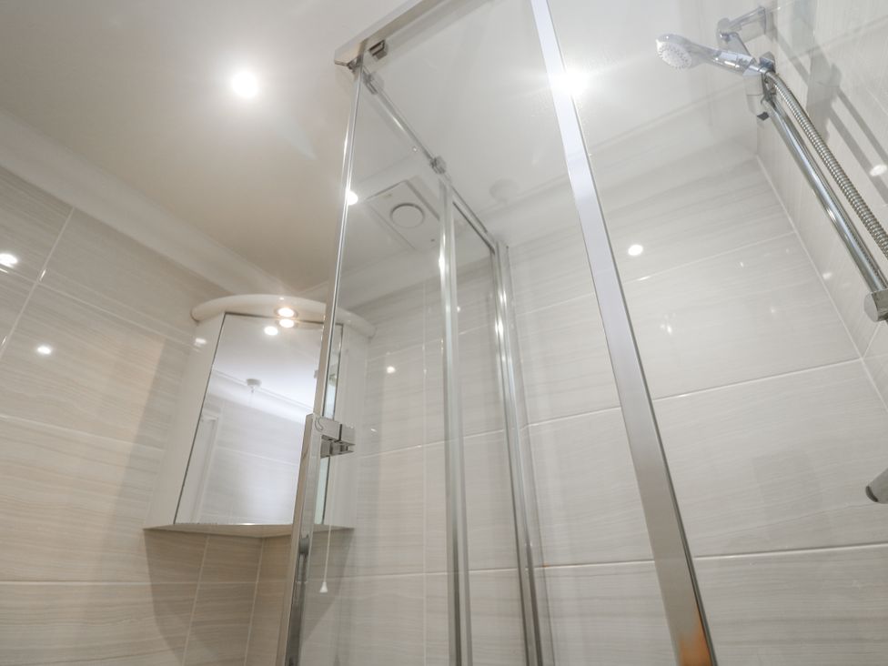 A shower with glass doors and a mirror at Golva in Carbis Bay