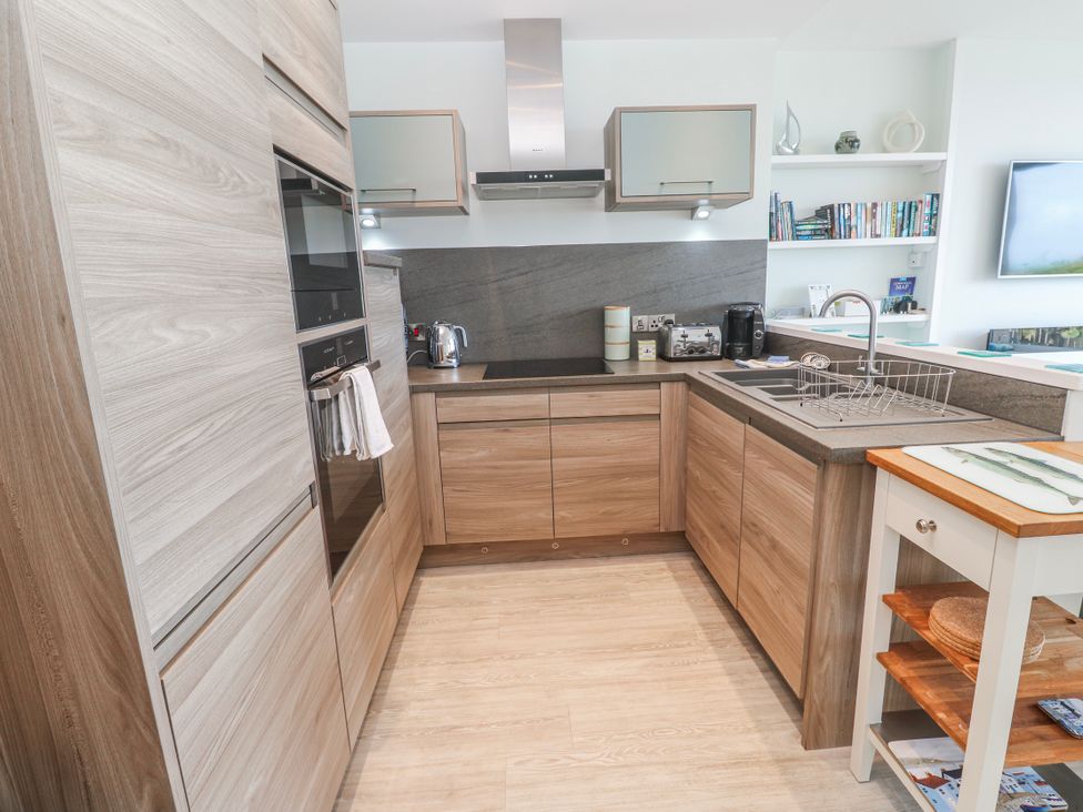 A kitchen with wood cabinetry and appliances at Island View in Carbis Bay