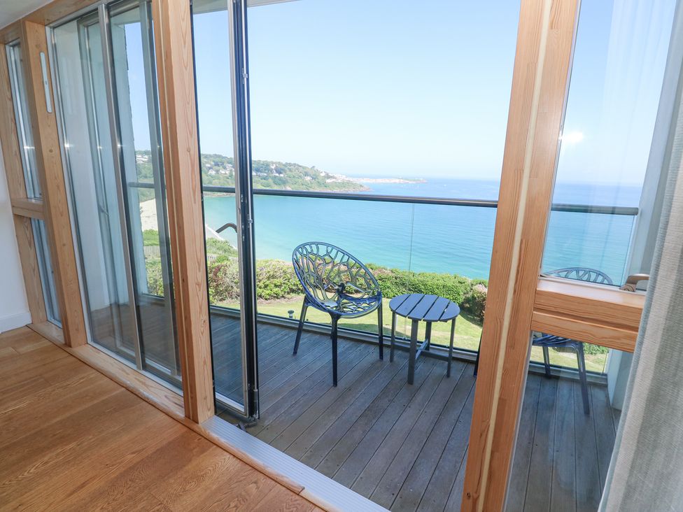 A balcony with two chairs and a small table overlooking the sea at Kittiwake in Carbis Bay