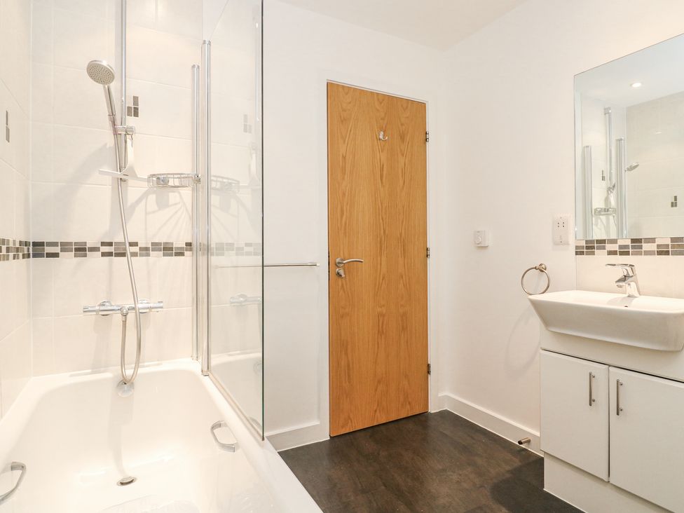 A bathroom with bathtub shower and sink cabinet with mirror at Kittiwake in Carbis Bay