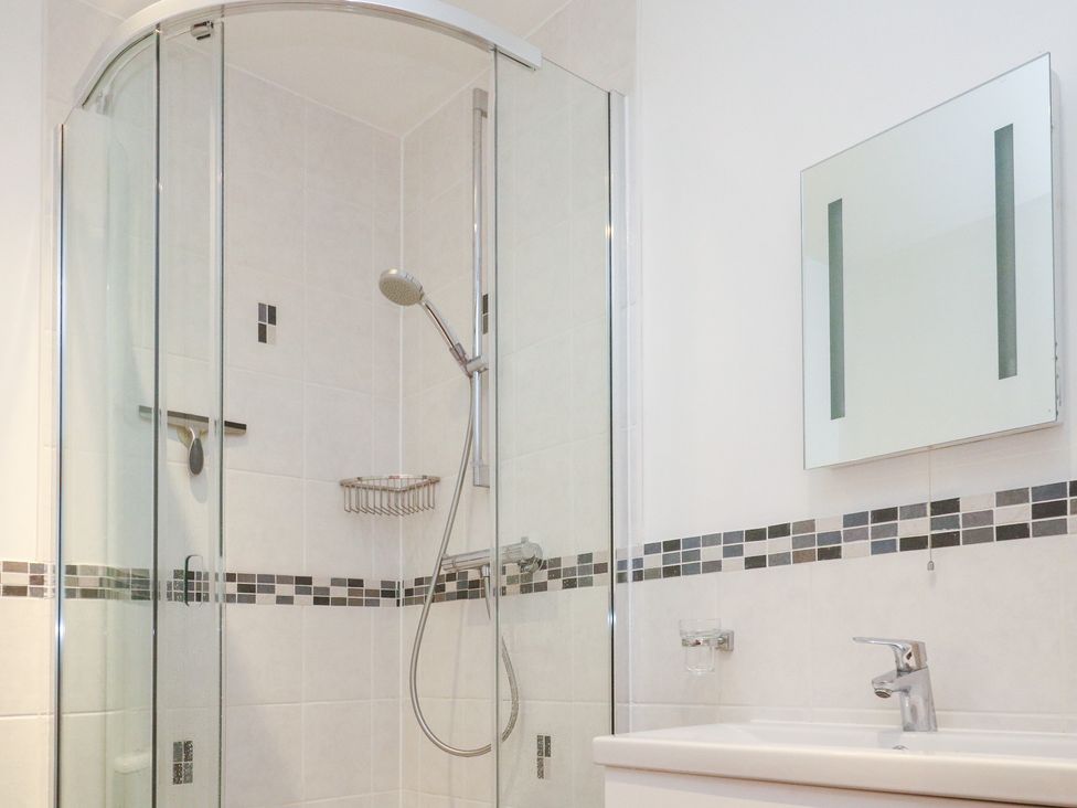 A bathroom with a shower and mirror at Kittiwake in Carbis Bay