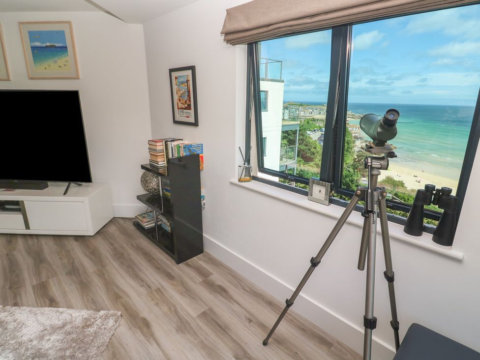 A living room with a telescope and bookshelves at Oceania St Ives