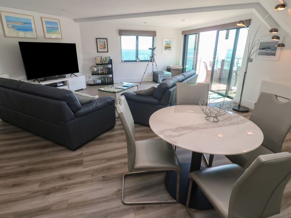 A living room with a television and dining table at Oceania in St Ives