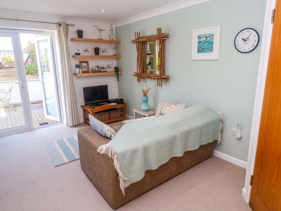 A living room with a sofa, tv, and shelving at Sea Breeze in Carbis Bay