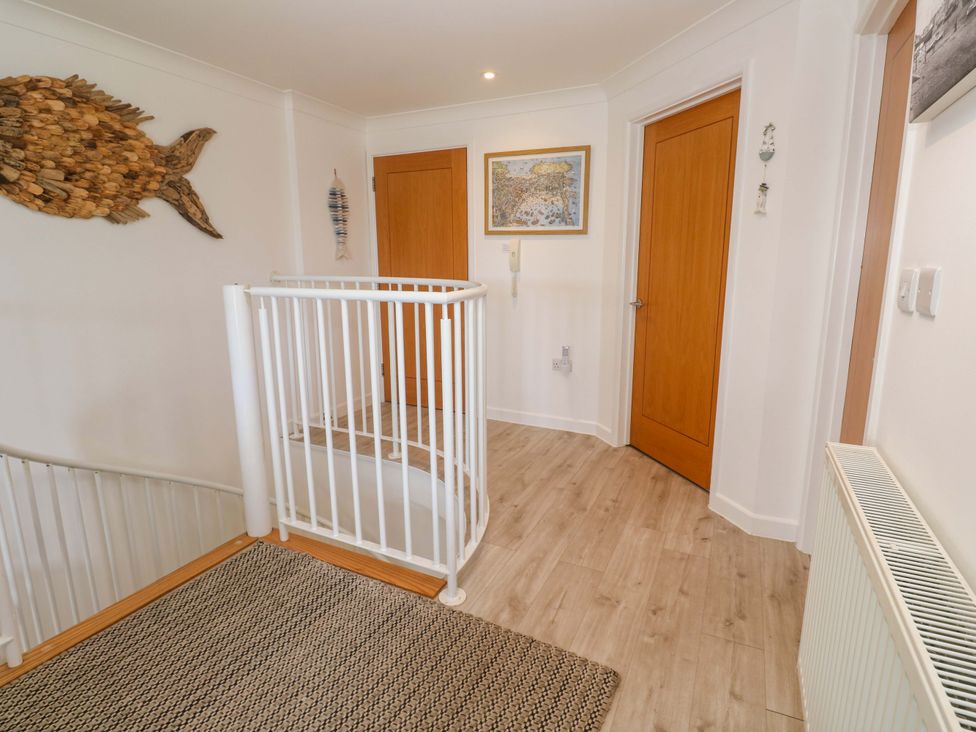 A hallway with a staircase and wooden doors at Sea Breeze in Carbis Bay