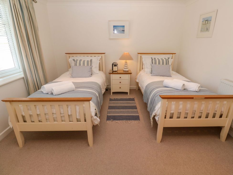 A bedroom with two beds and a side table at Sea Breeze in Carbis Bay