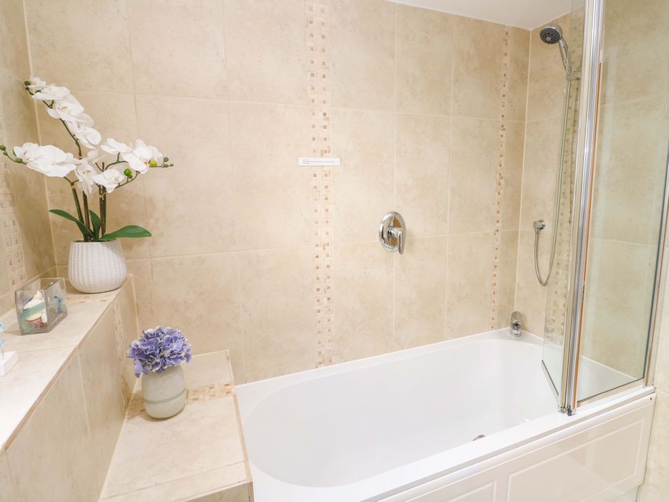 A bathroom with a bathtub and flower arrangement at Sea Breeze in Carbis Bay