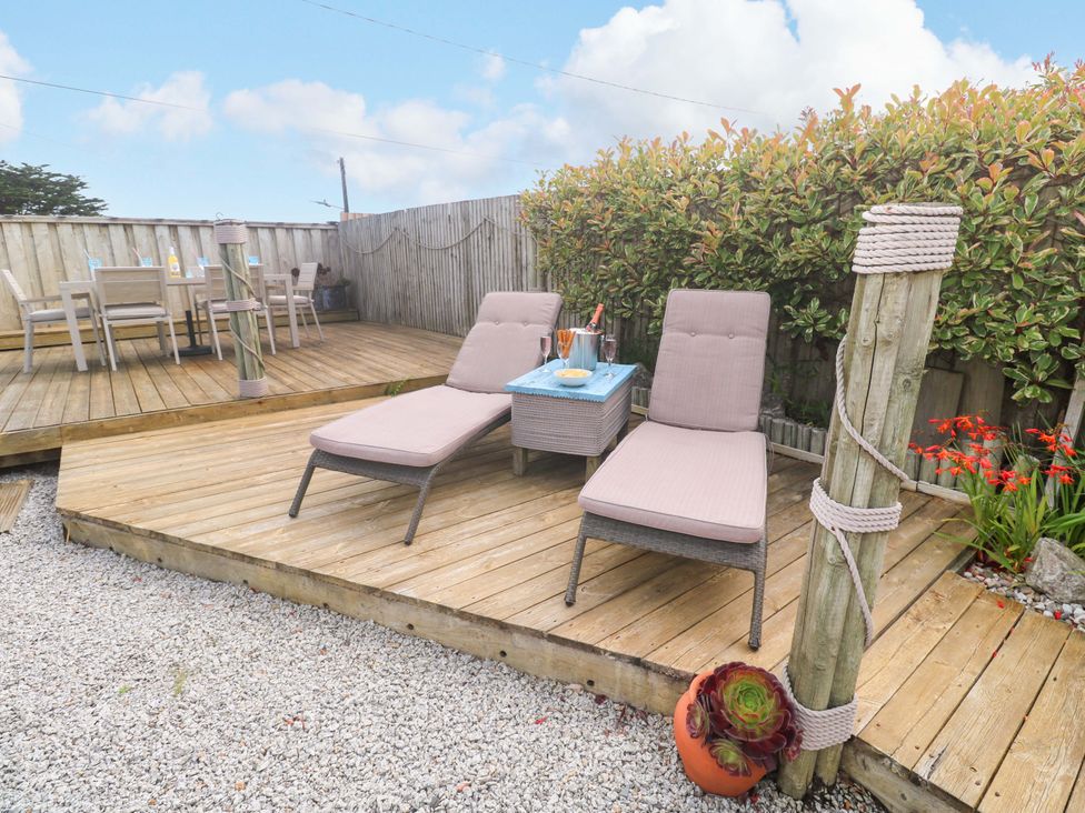 An outdoor area with sun loungers and a table at Sea Breeze in Carbis Bay