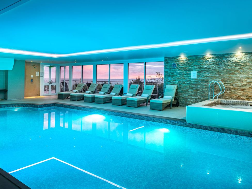 An indoor pool area with lounge chairs and jacuzzi at SeaMore in St Ives