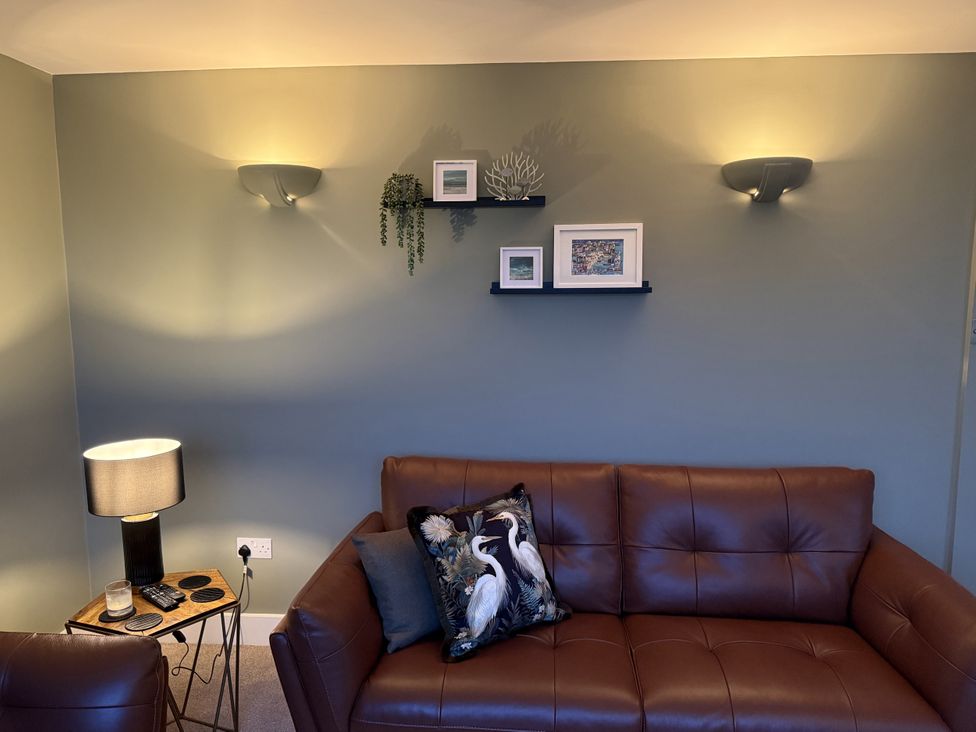 A living room with a brown sofa and a table lamp at Sowena in Carbis Bay
