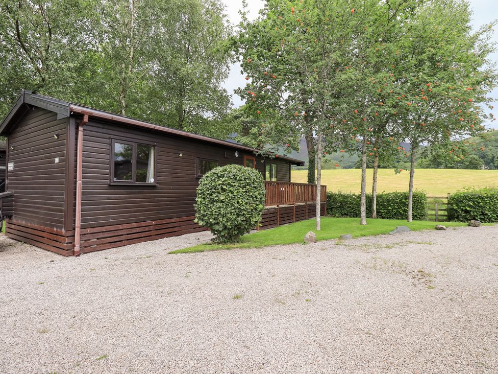 A cabin surrounded by trees and gravel area at Squirrels Leap Number 29, Burnside Park near Keswick