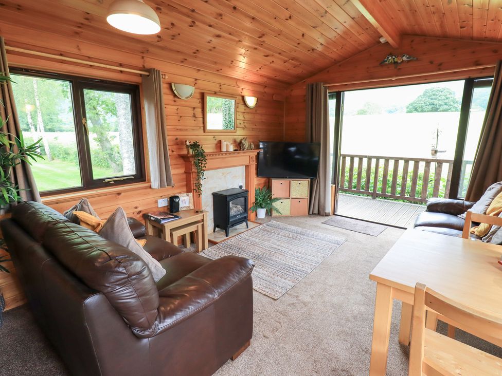 A living room with a sofa, table, and fireplace at Squirrels Leap, Number 29, Burnside Park near Keswick