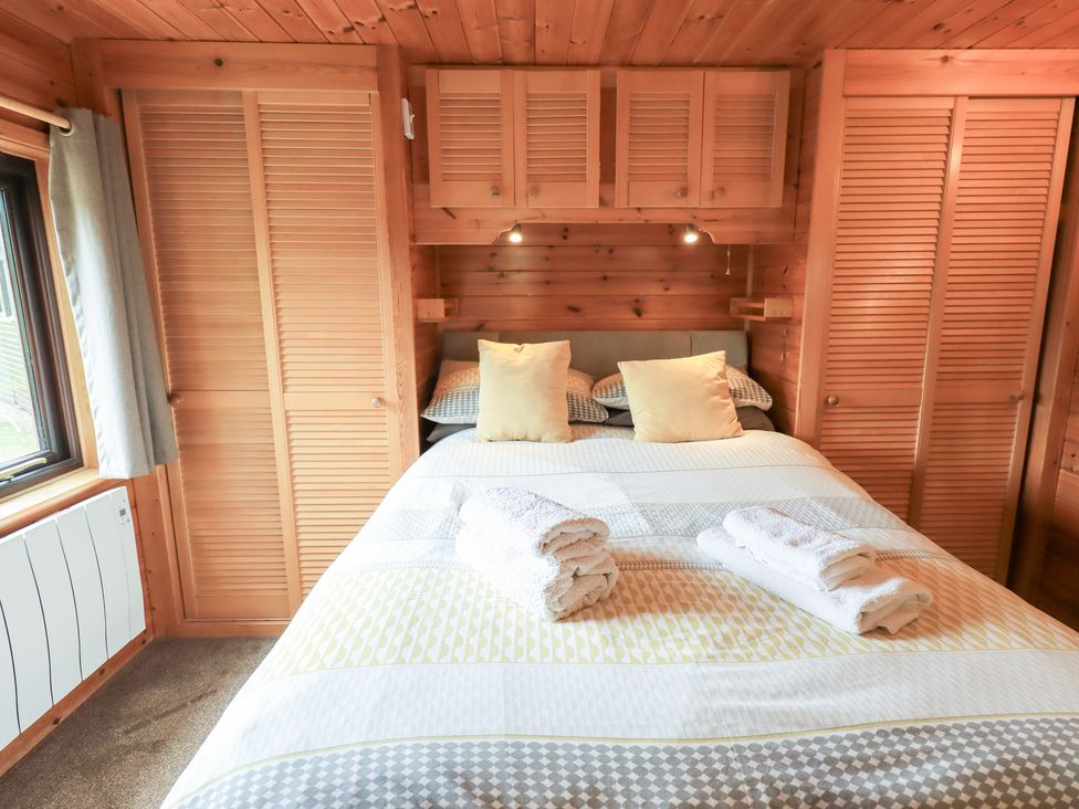 A bedroom with a bed and pillows at Squirrels Leap, Number 29, Burnside Park near Keswick
