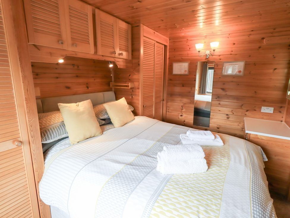 A bedroom with a bed and wooden furniture at Squirrels Leap near Keswick