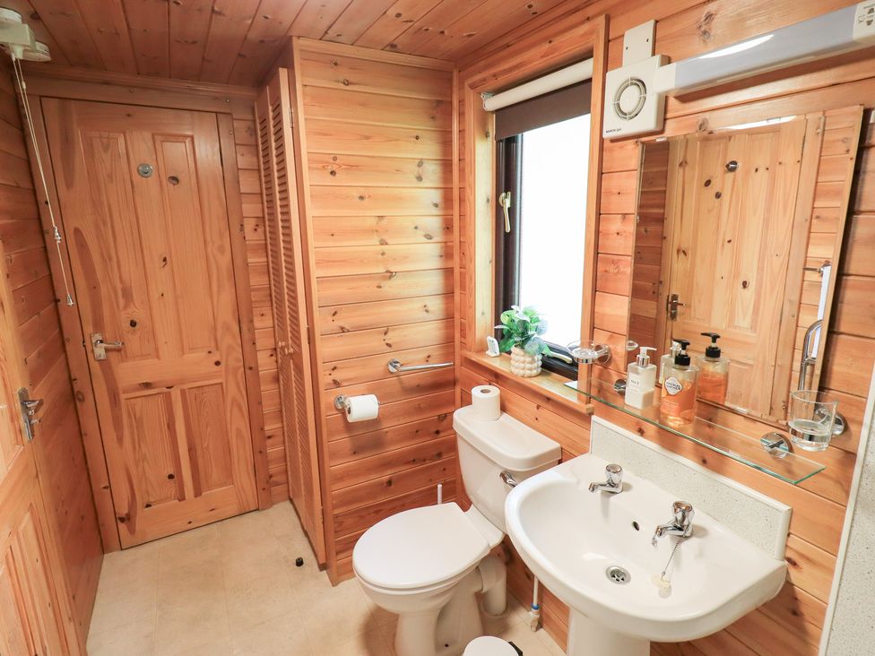 A bathroom with a sink, toilet, and mirror at Squirrels Leap, Number 29, Burnside Park near Keswick