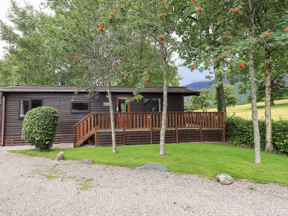 A cabin with a deck surrounded by trees at Squirrels Leap near Number 29, Burnside Park near Keswick
