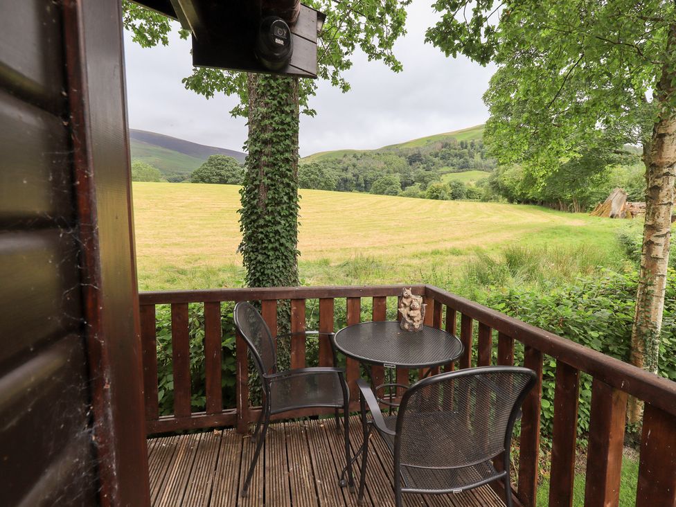 An outdoor seating area with a table and chairs overlooking a meadow at Squirrels Leap near Number 29, Burnside Park near Keswick
