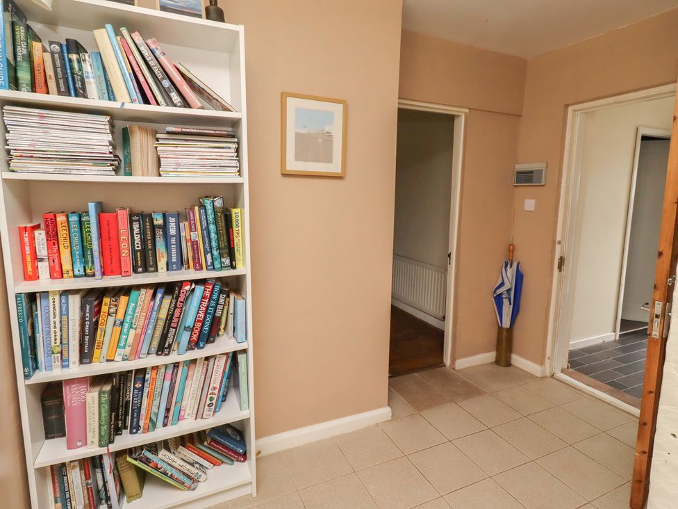 A bookshelf with books and magazines in a hallway at ASTA COTTAGE Cresswell