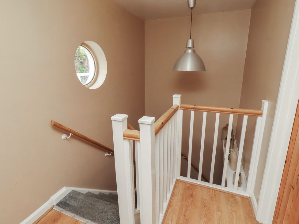 A staircase with a handrail and round window at ASTA COTTAGE Cresswell