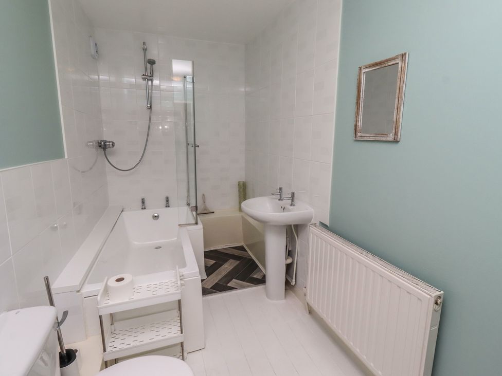 A bathroom with a bathtub, shower, toilet and sink at ASTA COTTAGE in Cresswell