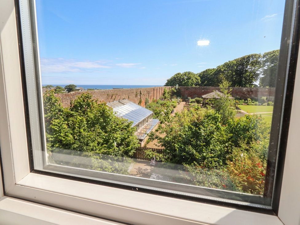 A view of a garden with a greenhouse and sea at ASTA COTTAGE in Cresswell