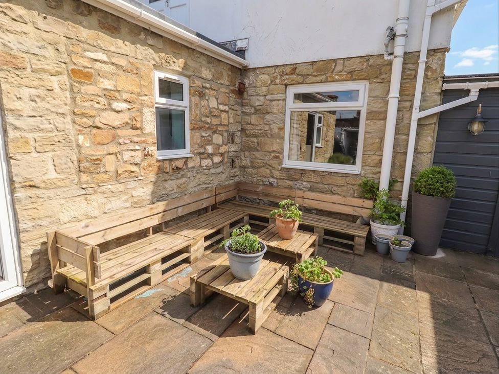 A garden with wooden benches and potted plants at ASTA COTTAGE Cresswell
