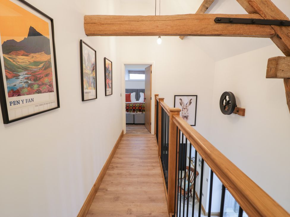 A hallway with wooden beams and artwork on the walls at Merddwr in Cerrigydrudion